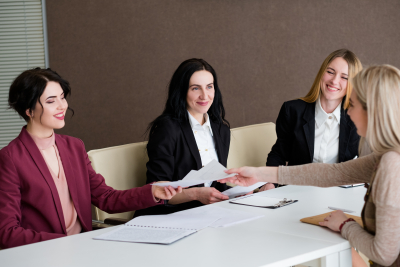 group of women from hr team smiling to a young work applicant during the interview