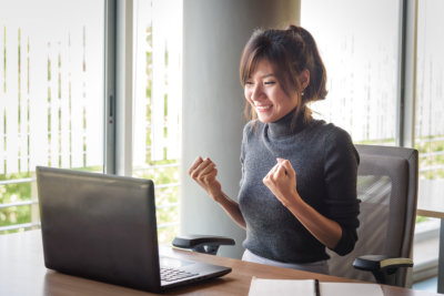 Celebrating successful young asian businesswoman with hands up
